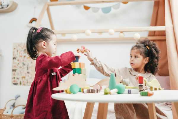 two young girls playing with blocks at a table