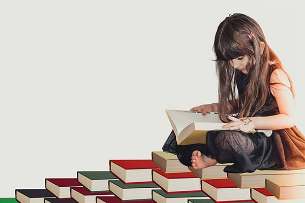 young girl with long hair sitting on a pile of books