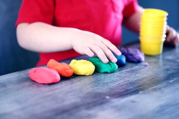 young boy wearing a red shirt playing with play dough