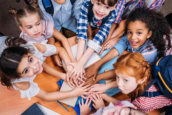 group of smiling kids with their hands together