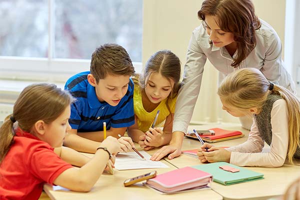 teacher helping four students with a paper